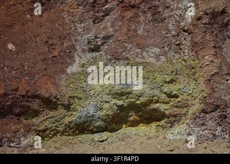 Close-up of a rock wall with intense shades of yellow and red, rich in mineral textures, Paliochori beach, Paliochori, volcanic rock, copper, nickel, Stock Photo