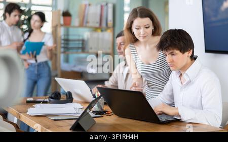 Employees working with laptops and paper documents in office Stock Photo