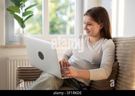 Girl Working With A Laptop On A Sofa, Surfing Social Media Stock Photo