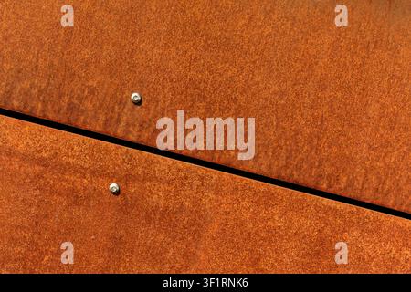 Rusted Corten steel plates texture background, close up of industrial metal cladding facade with joints and screws, geometric orange rust wall panel p Stock Photo
