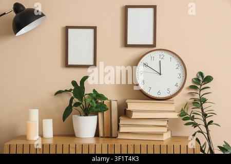 Modern home office interior with blank picture frames, desk lamp, and potted plants on a wooden cabinet Stock Photo