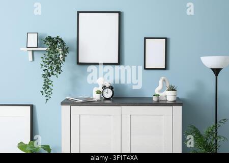 Modern home interior with blank picture frames on a light blue wall, Minimalist decor and green plants Stock Photo