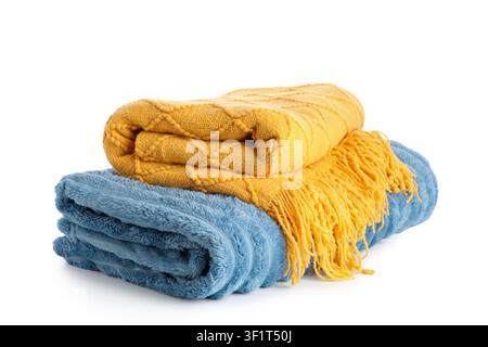 Stacked yellow knitted blanket with fringe and blue fluffy blanket, cozy home textiles for comfort and warmth, the blankets are isolated on a clean wh Stock Photo