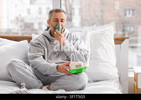 Mature man using nebulizer in bedroom Stock Photo