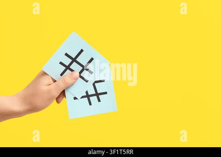 Female hand holding sticky notes with hashtags on yellow background Stock Photo