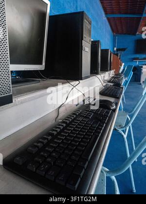 Empty computer laboratory equipped with desktop computers, monitors, keyboards, and student workstations in an educational institution. The classroom Stock Photo