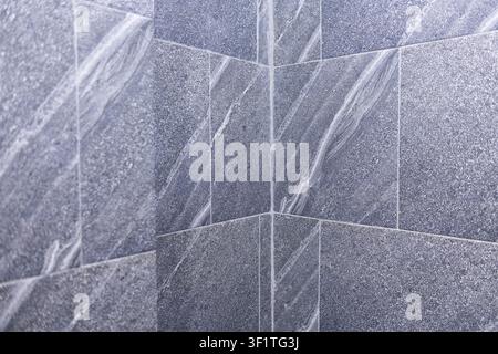 A gray stone tile corner with textured marble veins and subtle sheen creating calm minimalist bathroom interior mood Stock Photo