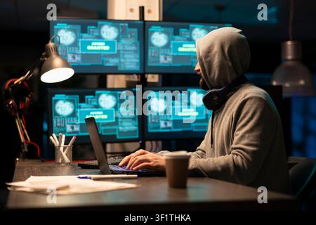 Male developer works late night in online environment, typing code and debugging network systems for improved productivity. White man looks at monitors, focusing on cybersecurity and information safety Stock Photo