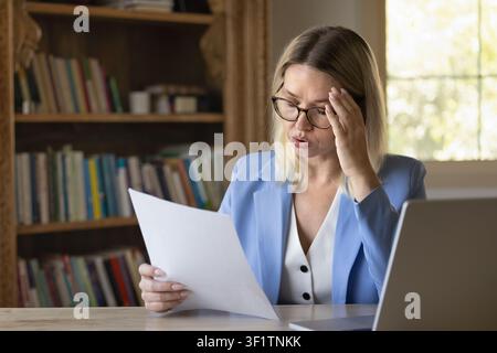 Stressed businesswoman reviewing documents at workplace desk Stock Photo