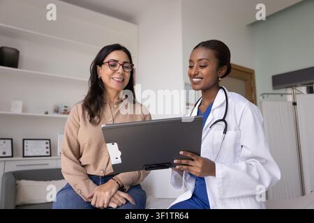 Happy young African doctor showing medical report to patient Stock Photo