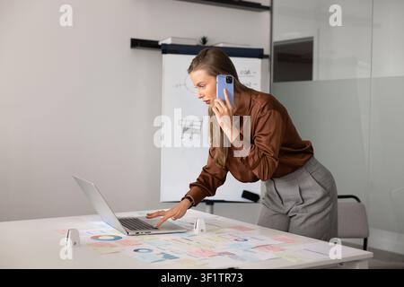 Businesswoman talking on phone while analyzing charts Stock Photo