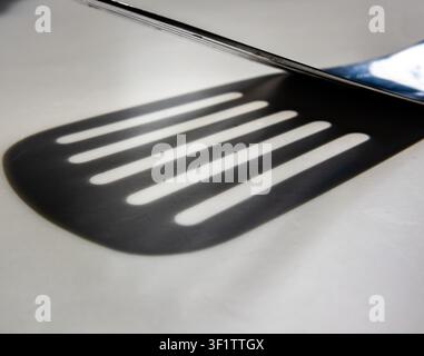 Kitchen spatula edge with parallel slots forming lined pattern in monotone Stock Photo