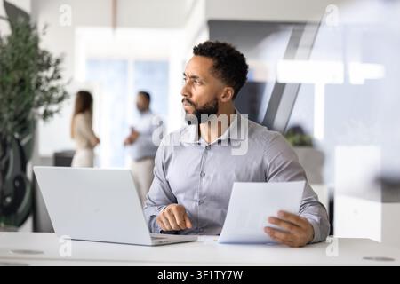Businessman holding report while looking away thoughtfully Stock Photo