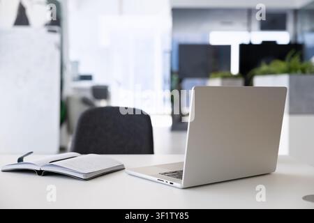 View to office desk with laptop and open notebook Stock Photo