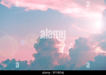 Sky showing soft pink and blue pastel clouds illuminated by a late afternoon sun flare, creating a peaceful and ethereal weather atmosphere during twi Stock Photo