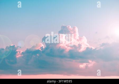 Sky creating a serene background, featuring soft pastel clouds reflecting pink and blue hues during sunset, enhanced by bright subtle lens flare addin Stock Photo