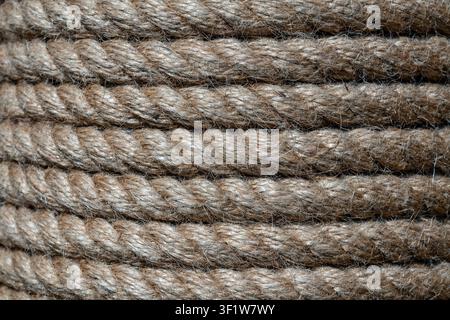 Natural jute hemp rope rolled into a coil, close up. Brown spool of linen rope texture on the background Stock Photo