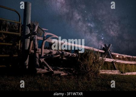View of a bull elk antler resting on a rustic wooden ranch fence under the starry night sky and the Milky Way in Picabo, Idaho, United States. Stock Photo