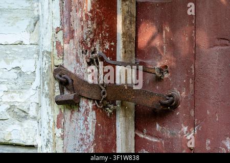 Very rusty padlock closing a wooden door, close up. An old wooden gate locked with an equally old rusty padlock. Vintage background Stock Photo