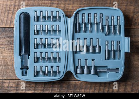 Open set of the interchangeable flat and hexagonal bits different sizes for screwdriver in plastic box. Working tools different types of metal steel h Stock Photo