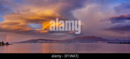 Panorama of a striking lenticular cumulus cloud formation lit orange at sunrise over the Derwent river and Wellington range at Hobart, Tasmania Stock Photo