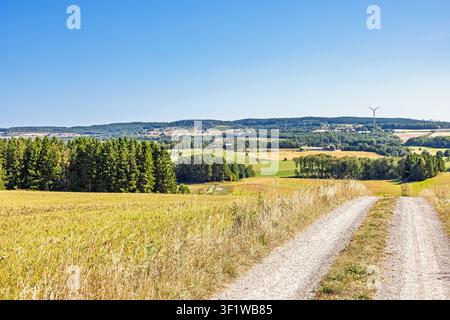Gravel road through agricultural fields and rolling hills in a rural landscape a sunny summer day Stock Photo
