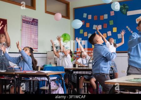 Happy elementary school students playing with balloons during an interactive classroom activity Stock Photo