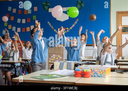 Happy elementary school students playing with balloons during an interactive classroom activity Stock Photo