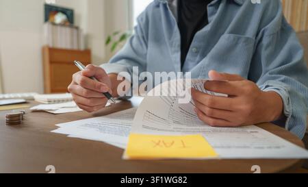 Cropped hands holding tax form with sticky note on desk for financial planning Stock Photo