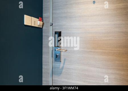 Hotel key card power switch beside digital door lock, room access shows a guest inserting a key card into the wall slot to activate electricity and in Stock Photo