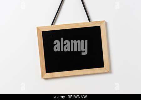 Blank blackboard with wooden frame hanging on white wall. Template mockup Stock Photo