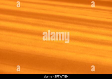 Abstract orange background showing sunbeams casting diagonal shadows and light stripes Stock Photo