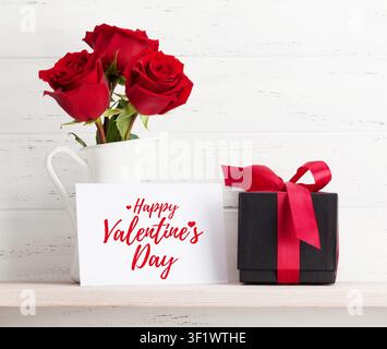 Valentines day greeting card with rose flowers and gift box on white wooden background - Photomontage Stock Photo