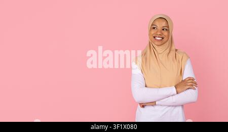 Confident young Black Muslim woman in beige hijab stands with crossed arms Stock Photo