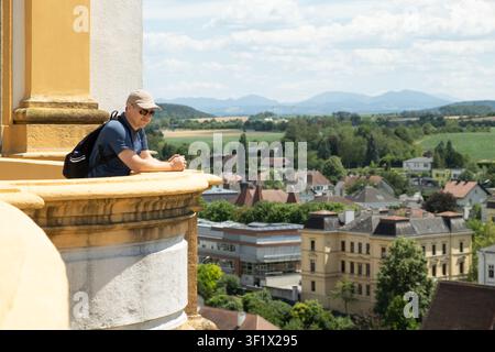 Male tourist with backpack looking down at the town from a historic balcony Stock Photo