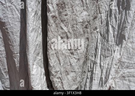 Close-up of draped grey linen fabric with rough wrinkled texture and harsh shadows. Stock Photo