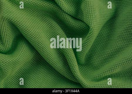 Horizontal close up of a bright green knitted mesh pique fabric texture draped in elegant soft wavy folds creating a clean comfortable clothing backgr Stock Photo