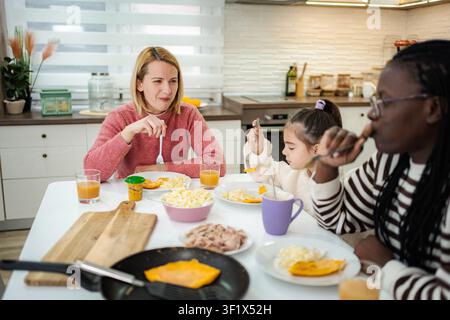 Diverse family enjoying breakfast together at home kitchen table Stock Photo
