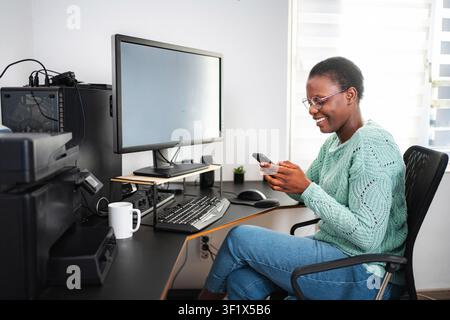 Young black woman using smartphone while working from home Stock Photo