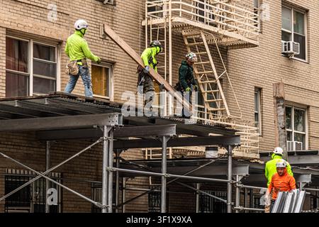 Construction workers on scaffolding perform building maintenance and repairs on an apartment building in Manhattan, New York. Stock Photo