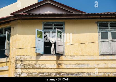 Open wooden window with a white curtain on a historic colonial shophouse in George Town, Penang, Malaysia. Stock Photo