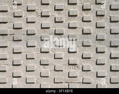 Horizontal close up of a heavily cream painted 3D brick wall surface with protruding bricks in a grid pattern, groove details, rough uneven texture Stock Photo