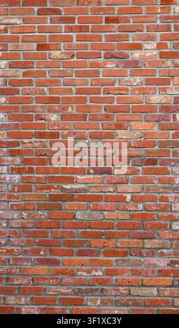 Vertical close up of a reclaimed red brick and mortar wall with varied red bricks Stock Photo