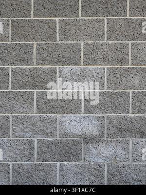 Vertical close up of a weathered decorative cinder block wall with black pebbles creating a spotted appearance Stock Photo