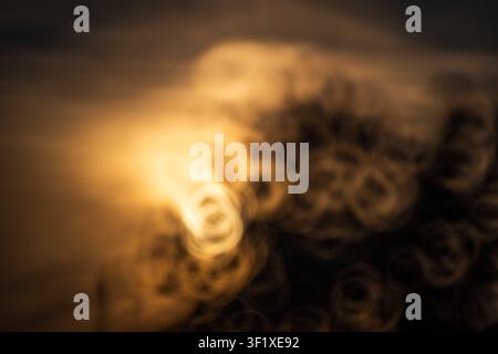An artistic, highly out of focus abstract background featuring glowing golden sunset light and unique ring-shaped donut bokeh patterns next to dark si Stock Photo