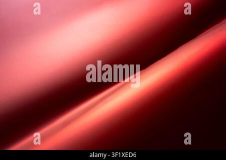 The image shows a close-up, abstract view of flowing red fabric. The fabric has a smooth, satiny texture with dramatic lighting that creates highlight Stock Photo