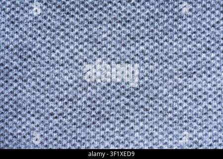 A close-up, full-frame view of a grey knitted fabric. The texture of the fabric is clearly visible, showing the interlinked loops of yarn. Stock Photo