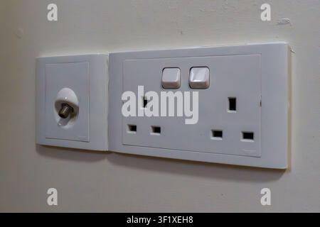 White wall-mounted electrical socket with two switches. Plug sockets and power switches are neatly arranged. Minimalist design suitable for home or of Stock Photo