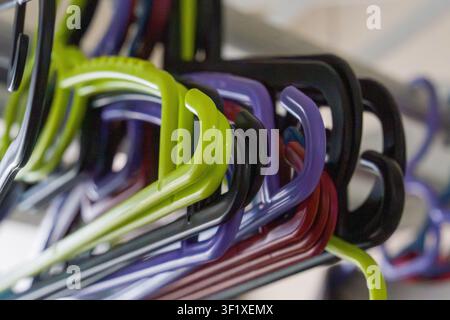 Colorful plastic hangers in close-up view. Stacked hangers display vibrant hues. Shallow depth of field emphasizes details. Hangers hang vertically in Stock Photo
