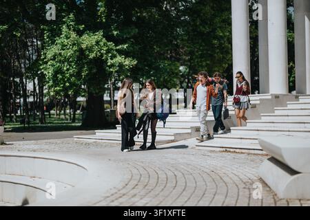 High school students walking and talking together on a sunny school campus near steps Stock Photo
